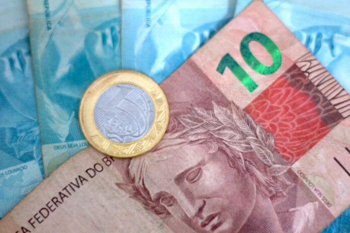 Moeda e cédula representando reserva de emergência e o Tesouro Reserva atrelado à Selic